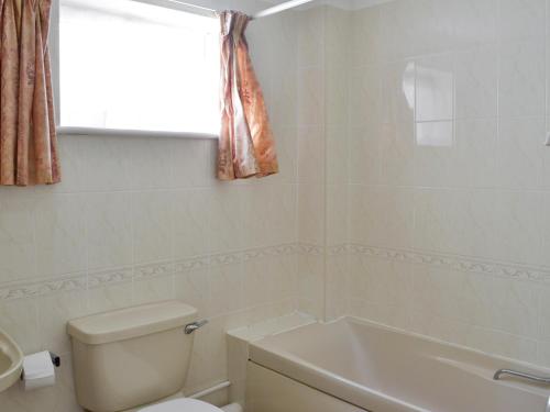 La salle de bains est pourvue de toilettes, d'une baignoire et d'une fenêtre. dans l'établissement Smugglers Haunt - Uk44513, à Hope-Cove
