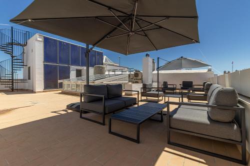 a patio with chairs and tables and an umbrella at Allo Apartments San Roque Bajo B in Cádiz