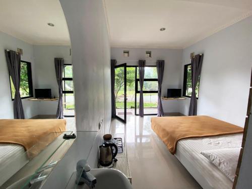 a bedroom with two beds and a hallway with windows at Shine River in Ciwidey