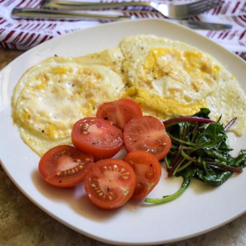 a plate of food with eggs and tomatoes and greens at Green Park Guest House in Dilijan