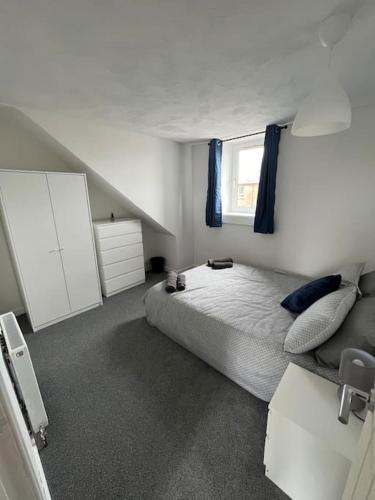 a white bedroom with a bed and a window at Homely 3 bed town centre flat in Peterhead