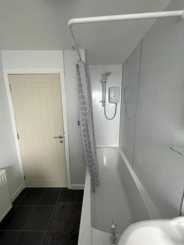 a white bathroom with a shower and a tub at Homely 3 bed town centre flat in Peterhead