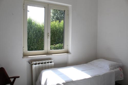 a white bedroom with a bed and a window at 80 m² Vista Mare in Policastro Bussentino