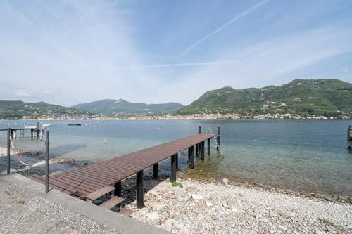a dock on a beach with mountains in the background at Villa Magnolie, accesso a lago in San Felice del Benaco