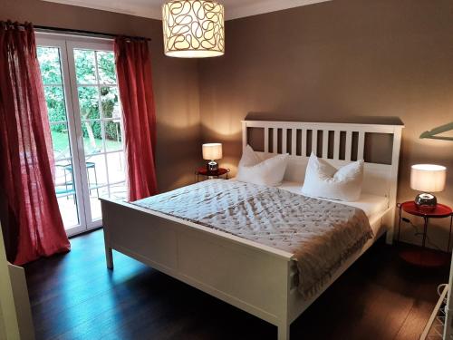a bedroom with a large white bed with red curtains at Seeliebe mit Sauna und nur 50 mtr. bis zum Strand in Senftenberg