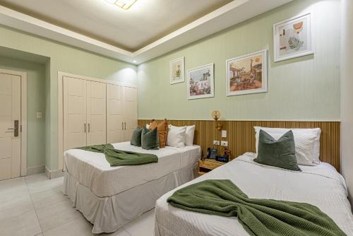 Hotel Stay Here Suites في سانتو دومينغو: سريرين في غرفة بجدران خضراء