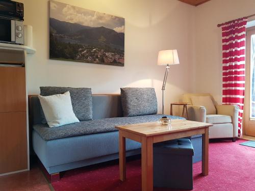 a living room with a blue couch and a table at Appartementhaus Hollaus in Zell am See