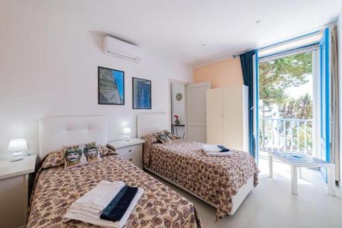 a bedroom with two beds and a large window at ToviMar Apartments in Taormina
