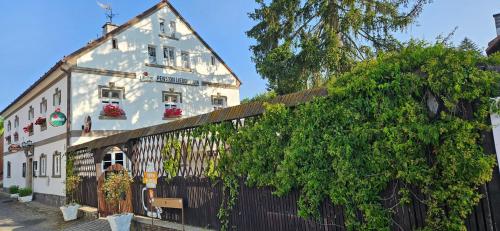 ein weißes Gebäude neben einem Zaun mit einem Baum in der Unterkunft Restaurant & Pension Liebenstein in Libá