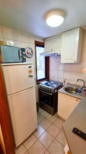 a kitchen with a white refrigerator and a sink at DEPARTAMENTOS TERMAS DE CHILLAN in Nevados de Chillan