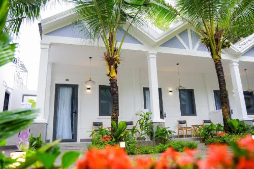 una casa blanca con palmeras delante en NatalieLe's Homestay, en Phu Quoc