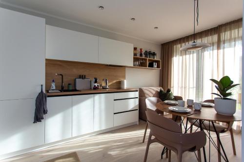 a kitchen and dining room with a table and chairs at Albatross RELAX seaside design apartment with terrace in Ķesterciems