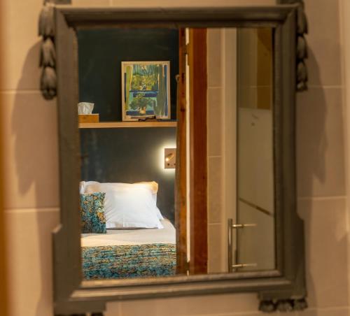 einem Spiegel, der ein Schlafzimmer mit einem Bett reflektiert in der Unterkunft Les Jardins de Baracane in Avignon