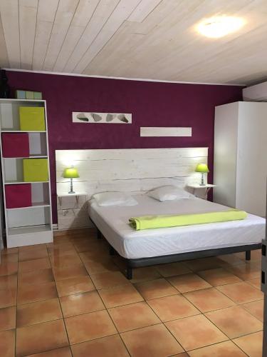 - une chambre avec un lit et un mur violet dans l'établissement Gites de la Massane, à Argelès-sur-Mer