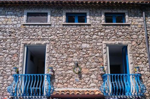 a stone building with blue balconies in front of it at ToviMar Apartments in Taormina