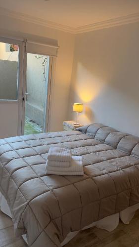 Un dormitorio con una cama grande con una lámpara y una ventana. en 25puntocinco deptos Tandil, en Tandil