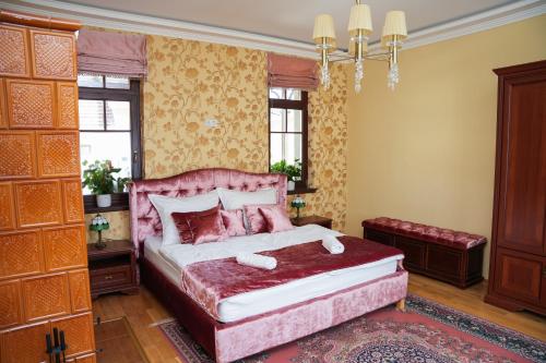 a bedroom with a pink bed and a chandelier at Várkert Deluxe Apartmanház in Miskolc