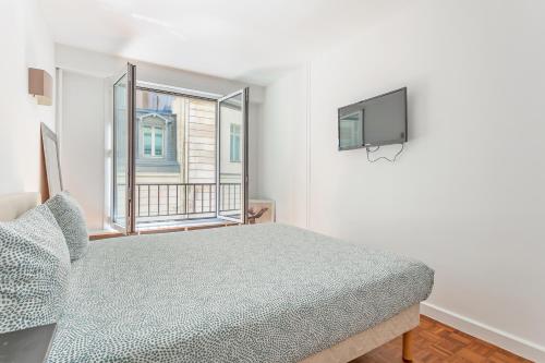 um quarto com uma cama, uma televisão e uma janela em La Suite d'Avenue Foche em Paris