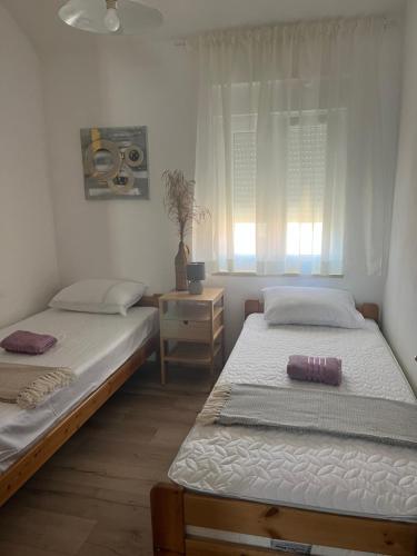 two twin beds in a room with a window at Apartman Sea story Mali Lošinj in Mali Lošinj