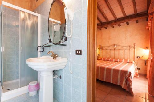 baño con lavabo, espejo y cama en Fattoria di Mugnano en Colle Val D'Elsa