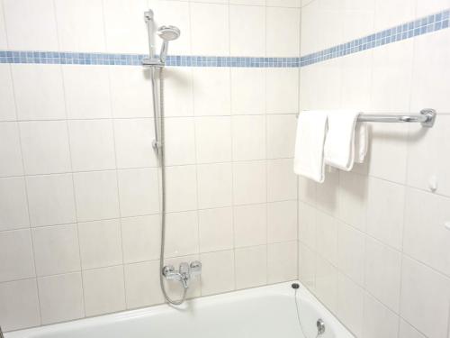 a white tiled bathroom with a shower and a tub at Tauern in Kaprun