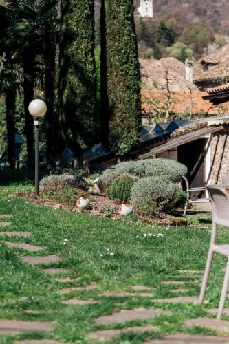 a yard with a chair and a lamp in the grass at Angerburg Blumenhotel in Appiano sulla Strada del Vino
