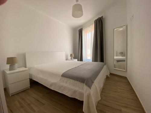 a white bedroom with a large bed and a mirror at Casa da Amoreira in Odeceixe