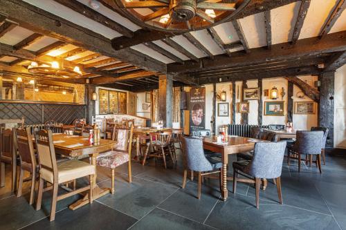 um restaurante com mesas e cadeiras de madeira e um tecto em The Jamaica Inn, Bodmin, Cornwall em Bolventor