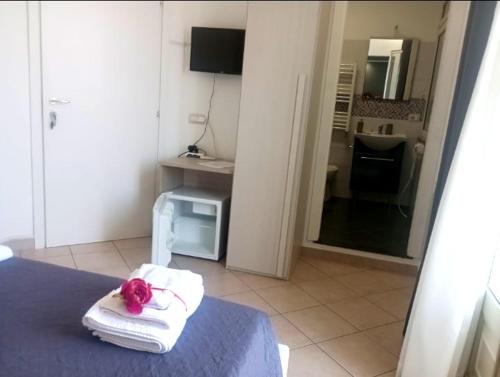 een kamer met een bed met handdoeken en een televisie bij Villa longardi in Zafferana Etnea