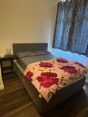 a bedroom with a bed with a flower blanket on it at Nice and Pleasant in Thornton Heath