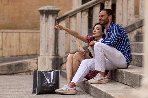 a man and a woman sitting on the stairs at PALAZZO DEL CAPITANO Wellness & Relais - Luxury Borgo Capitano Collection in San Quirico dʼOrcia
