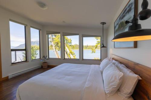 sypialnia z dużym białym łóżkiem i oknami w obiekcie Tree Fern Guest House w mieście Tofino