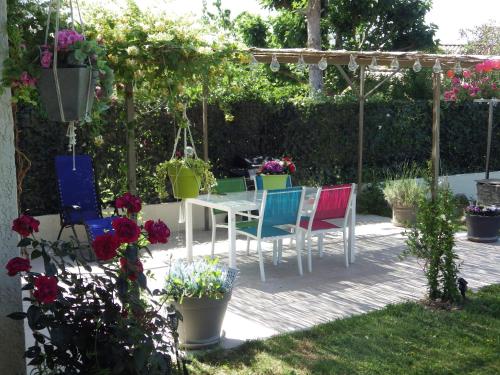 un patio con tavolo, sedie e fiori di Chez Noêlle a LʼIsle-sur-la-Sorgue