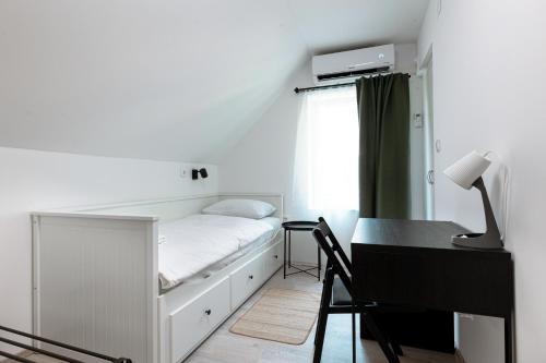 a white bedroom with a bed and a desk at House Pavel in Osijek