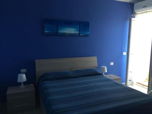Dormitorio azul con cama y pared azul en Baia di Copanello IMMINENS MARI, en Copanello