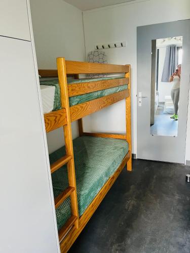 a room with bunk beds and a woman standing in a doorway at studio 4 pers praloup 1600 in Uvernet-Fours
