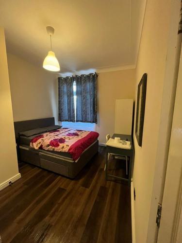 a bedroom with a bed and a table and a window at Nice and Pleasant in Thornton Heath
