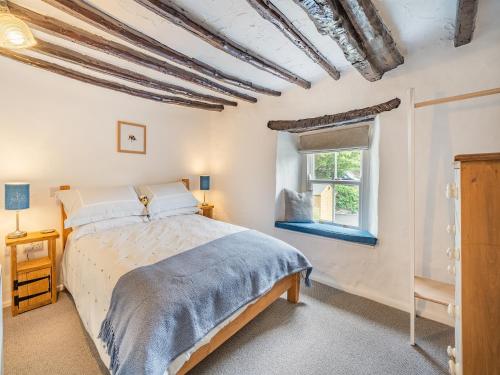 a bedroom with a bed and a window at Rose Garden Cottage in Heversham