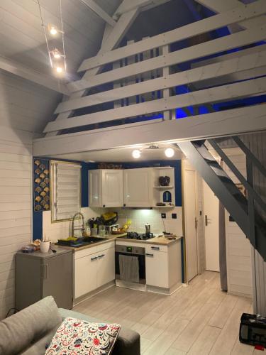 a small kitchen with white cabinets and a staircase at Le chalet Normand in Merville-Franceville-Plage