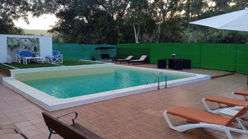 einen Pool mit 2 Stühlen und einem Sonnenschirm in der Unterkunft El Salao in Olvera