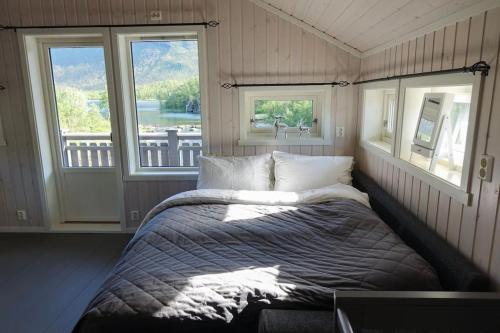 a bed in a room with two windows at Stor hytte med 98" TV, PS5, grillhytte etc in Narvik