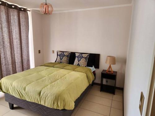 a bedroom with a bed with a green comforter at Cómodo departamento diario. in Iquique