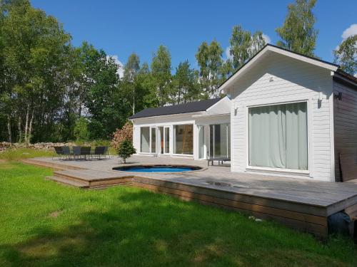 a house with a deck and a swimming pool at Cabin in the forest with Spa bath in Västra Torup
