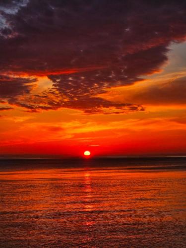a sunset over the ocean with the sun in the sky at Batumi Palm Hotel in Batumi