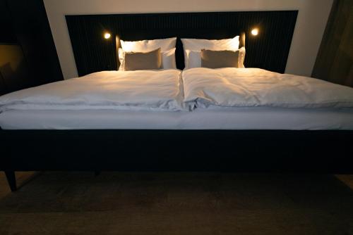 ein großes Bett mit weißer Bettwäsche und Kissen in der Unterkunft E D E L H O F . R O O M in Jois