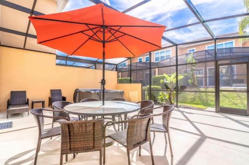 a table and chairs with a red umbrella on a patio at TVPM-2678TWithRO townhouse in Orlando