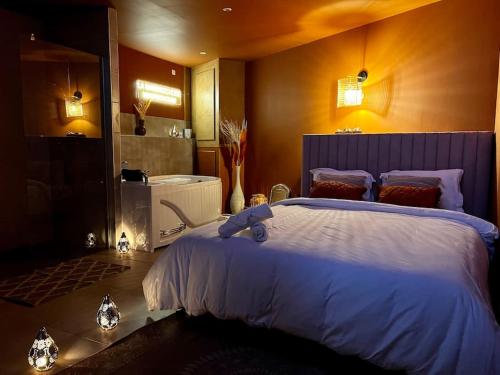 ein Schlafzimmer mit einem großen Bett und einer Badewanne in der Unterkunft La Marrakechoise - Suite Balnéo in Tourcoing