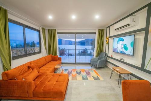 a living room with an orange couch and a television at Villa Blue Coast I & II wBeach and Great Sea View - KALKAN in Kas