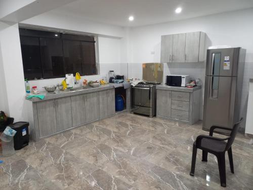 a large kitchen with stainless steel appliances and a chair at Casa de Campo Las Tujas in Lunahuaná