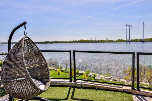 un banco de ratán sentado en un balcón con vistas al río en River Waterfront Paradise Vacation Home, en Terrebonne